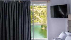 A bedroom with a large window, a bed, and a television on the wall. - Hotel Nova El Peñol (El Peñol)