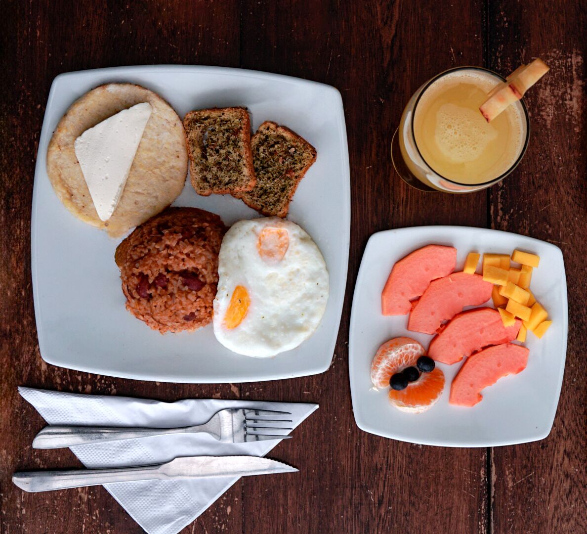 Ein Frühstücksteller mit Toast, Rührei und dazu Obst und Käse.