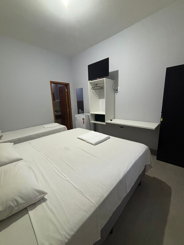 A hotel room with two beds, a small desk, a mirror, and a TV mounted on the wall. - Flat Thermas Olimpia unidade 1 (Olimpia)