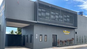 Un edificio moderno con fachada gris, un ventanal grande y un letrero que dice "Fidel Thomas Olimpia".