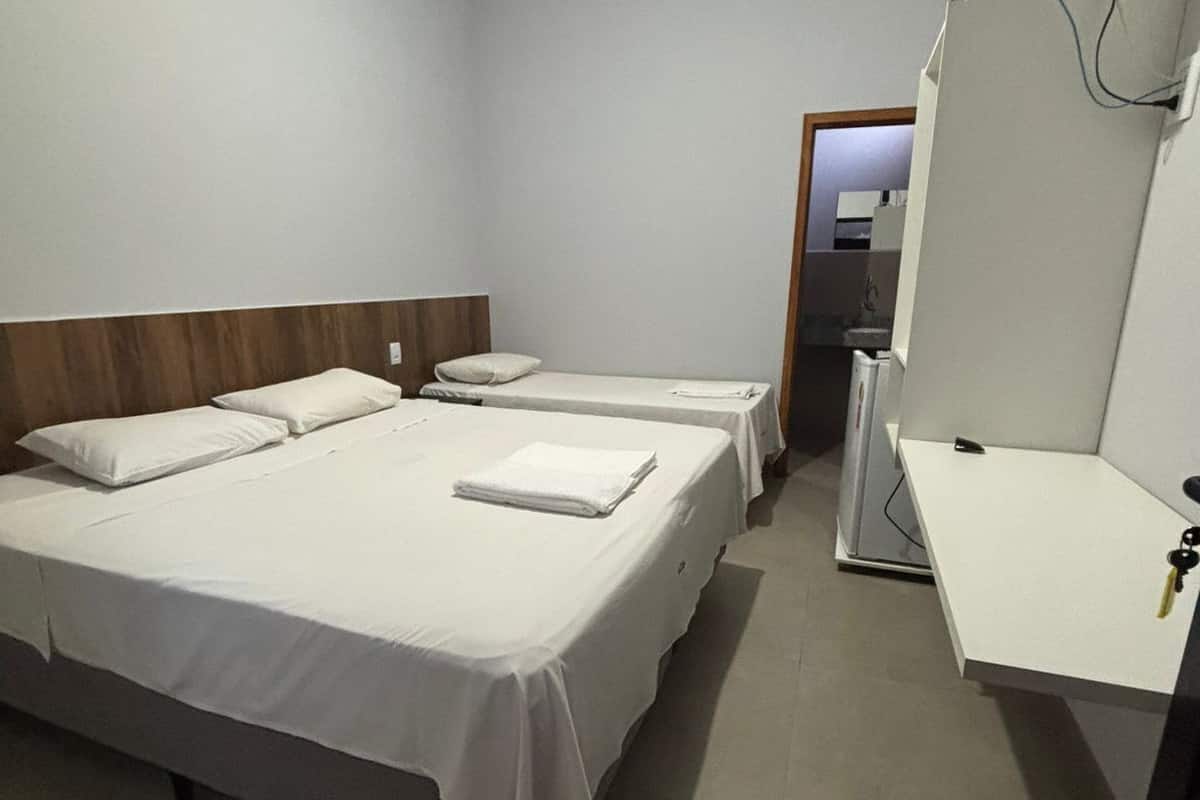 Habitació d'hotel amb dos llits, un escriptori, un televisor i un mirall.