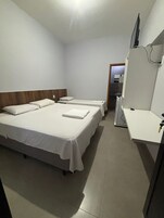 Quarto de hotel com duas camas, uma escrivaninha, uma televisão e um espelho.