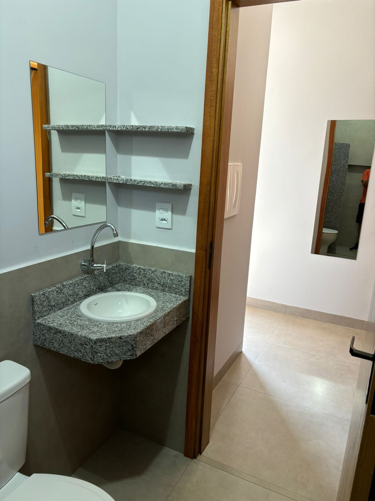 A bathroom with a granite sink, a mirror, and a toilet.