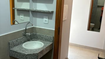 A bathroom with a granite sink, a mirror, and a toilet.