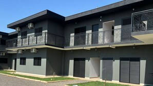 Un edificio residencial moderno de varios pisos con balcones, unidades de aire acondicionado y un exterior limpio y bien conservado.