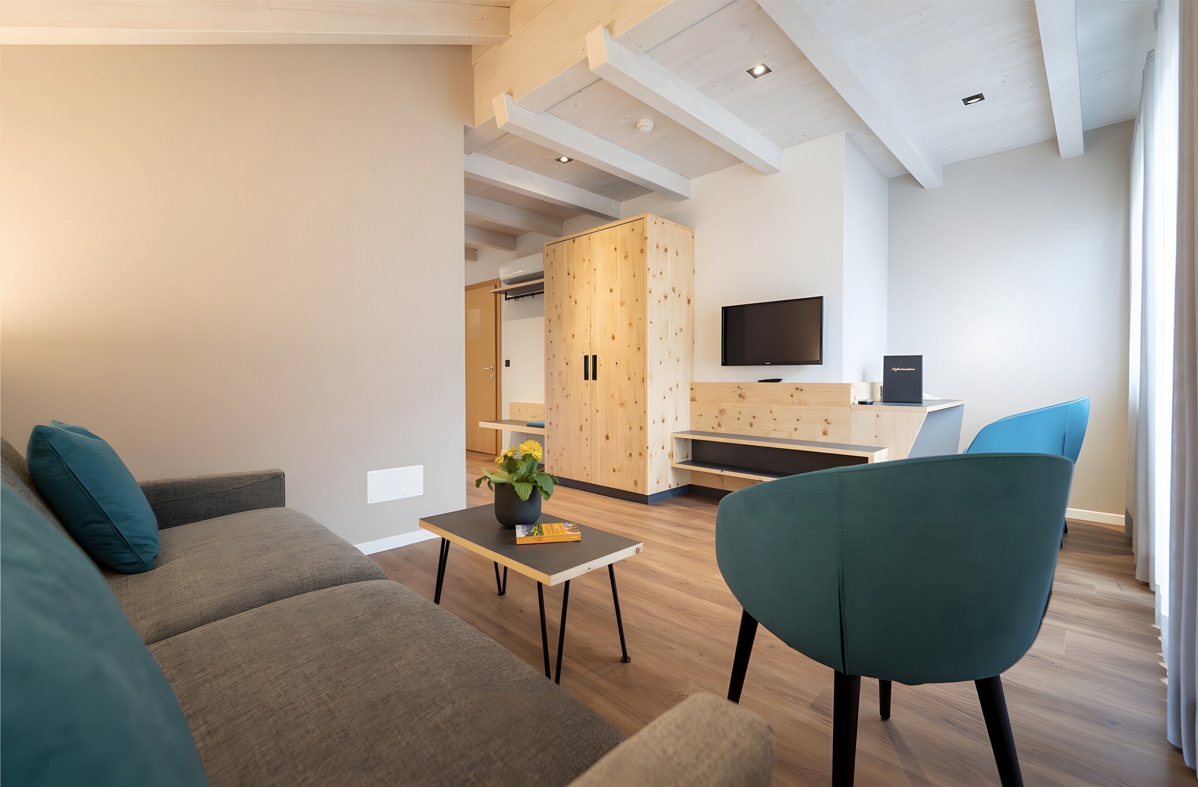 A modern living room with a sofa, a coffee table with a plant, a TV, and a desk area.