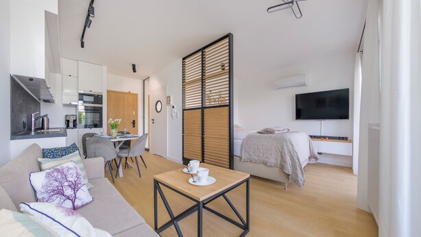 A modern living space with a kitchen, dining area, and bedroom. - Apartamenty Sun & Snow Perła Mierzei (Sztutowo)