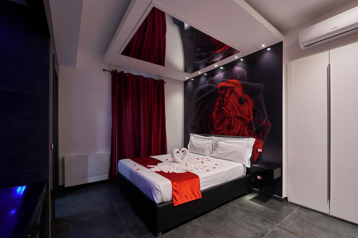 A modern bedroom with a black and white bed, red curtains, and a large wall mural.