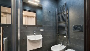 Un bagno moderno con box doccia in vetro, lavandino bianco, bidet e portasciugamani.