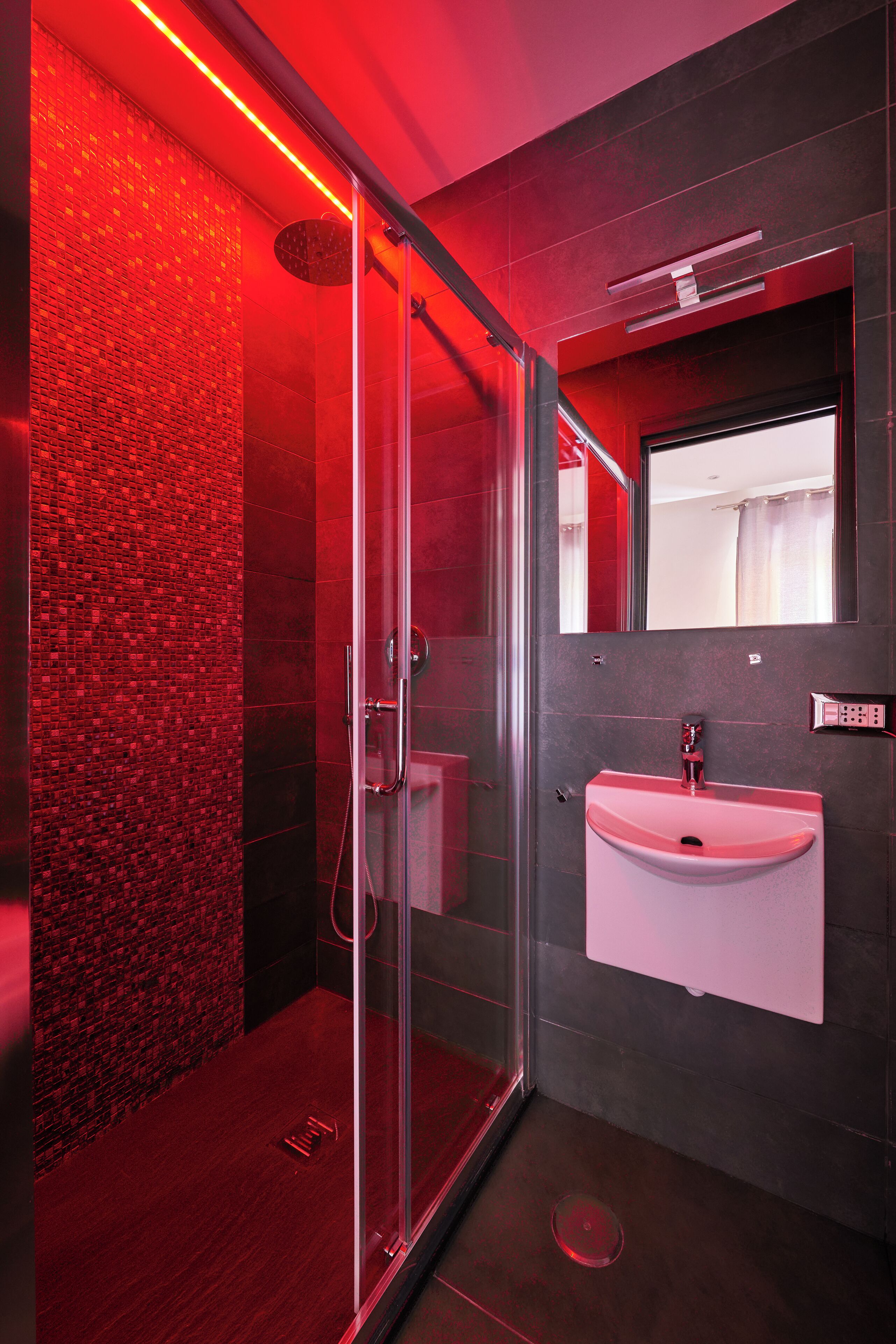 A modern bathroom with a glass shower enclosure, a white sink, and a mirror above it.