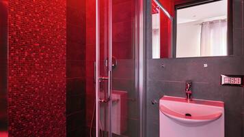 Ein modernes Badezimmer mit Duschkabine aus Glas, einem weißen Waschbecken und einem Spiegel darüber.