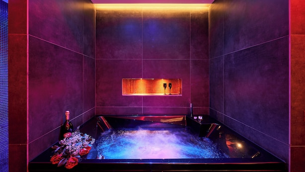 Una moderna spa con pavimento riscaldato, una piccola nicchia con uno specchio e una bottiglia di champagne a sinistra.
