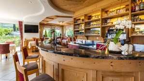 A modern kitchen with wooden cabinetry, a granite countertop, and a dining area with chairs and a table. - Room 'Silber Zimmer 2' with Mountain View, Wi-Fi and Air Conditioning (Tirolo)