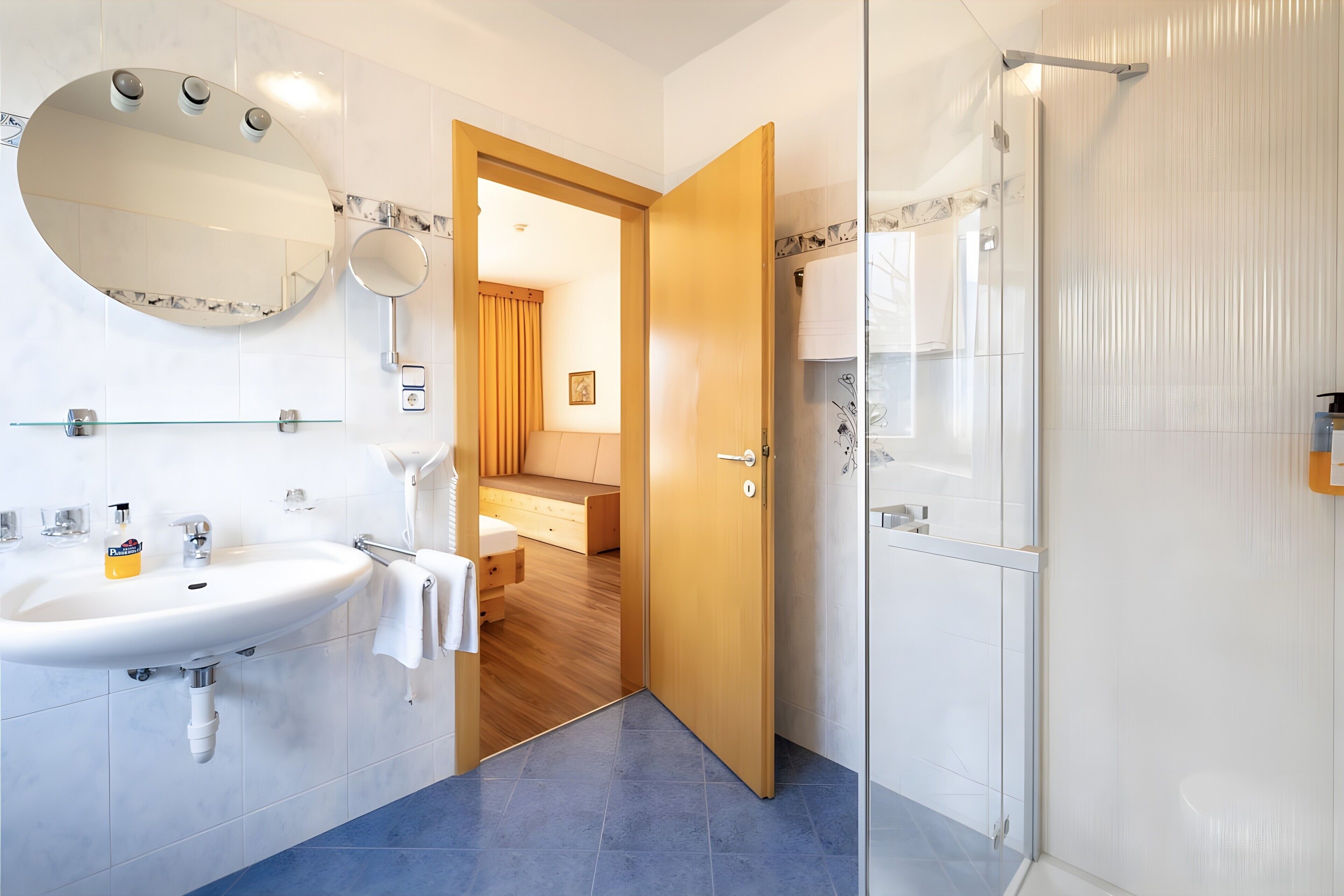 A bathroom with a sink, mirror, and shower.