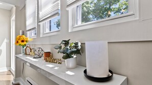 A modern kitchen with a white countertop, a vase with sunflowers, a welcome sign, and a potted plant. - Charming 2BD W/ Parking 15 Mins from Downtown (Milwaukee)