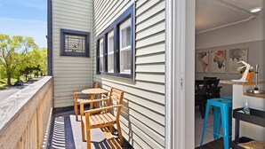 A wooden deck with a table and chairs, a blue stool, and a small kitchen area with a sink and countertop. - Charming 2BD W/ Parking 15 Mins from Downtown (Milwaukee)