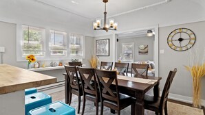 A dining area with a wooden table and chairs, a chandelier, and artwork on the walls. - Charming 2BD W/ Parking 15 Mins from Downtown (Milwaukee)
