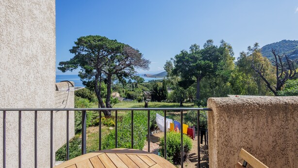 Un balcón con vistas a un jardín y una cadena montañosa distante.