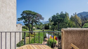 Un balcón con vistas a un jardín y una cadena montañosa distante.