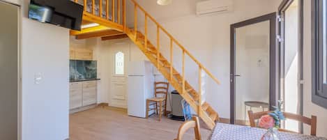 A kitchen with wooden flooring, a built-in stove, and a wooden staircase.