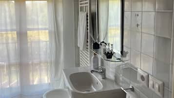 A bathroom with a white sink, a large mirror, and a bathtub.