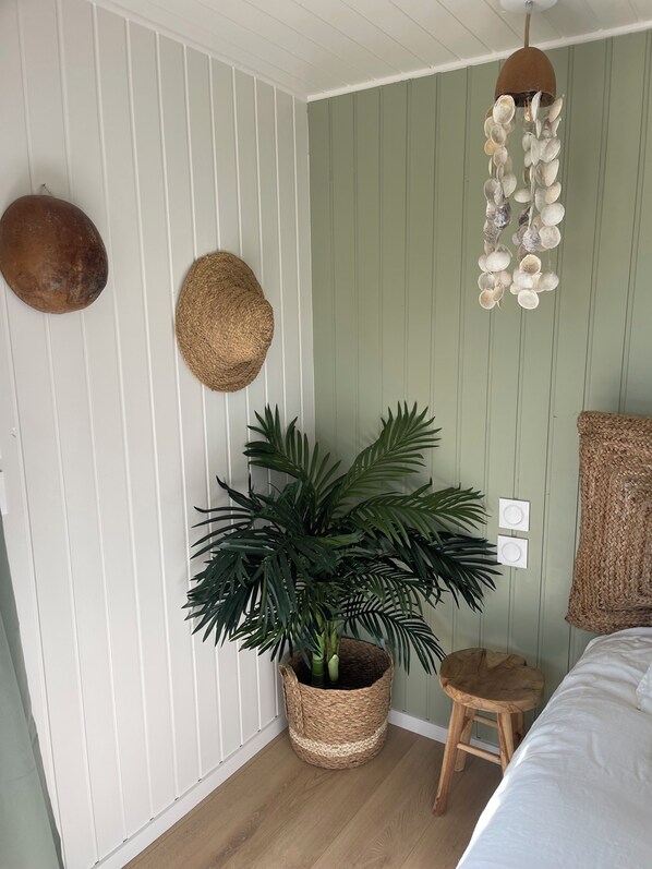 Una habitación con una planta grande en maceta, un colgador de luz y una cesta tejida.