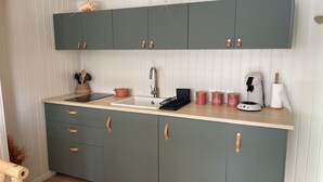 Una cocina moderna con encimera blanca, un lavamanos y una cafetera.