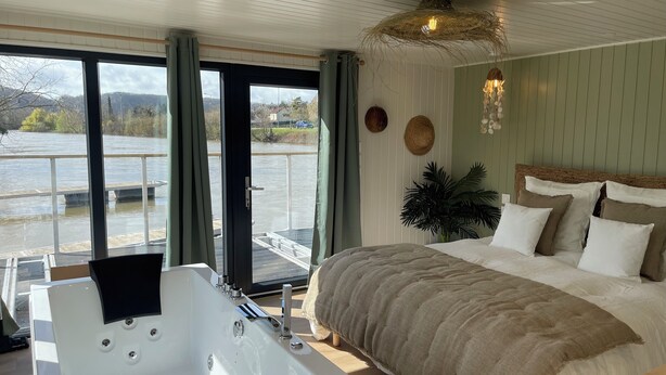 Un dormitorio con una cama grande, una bañera y vistas a un río.