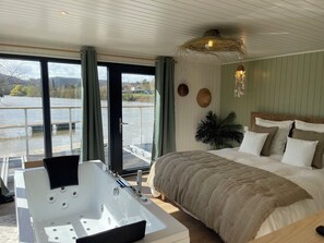 Un dormitorio con una cama grande, una bañera y vistas a un río.