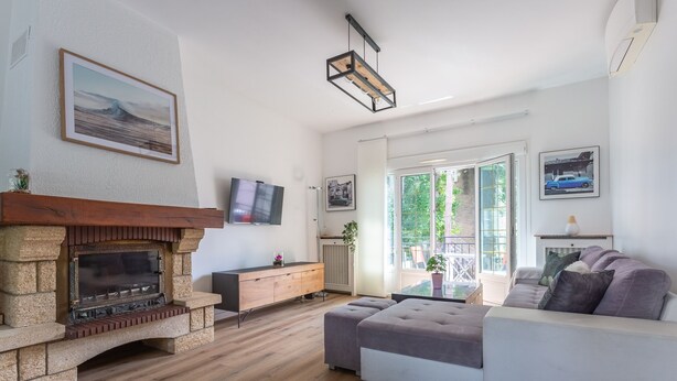 Una sala de estar con chimenea de piedra, un sofá, un televisor y un ventanal grande.