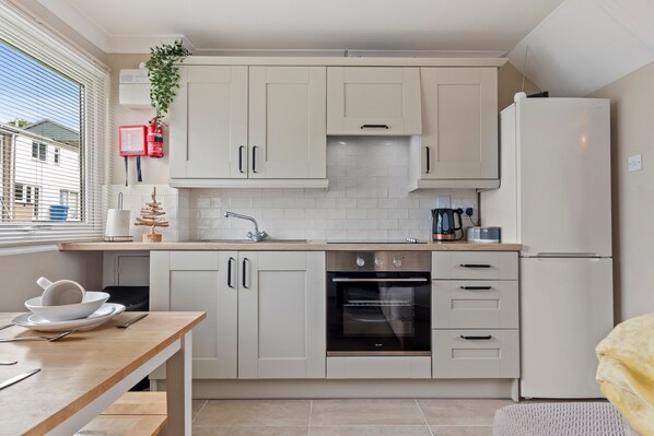 A modern kitchen with white cabinets, a built-in oven, and a refrigerator.