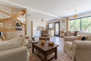 Ein geräumiges Wohnzimmer mit einer Holztreppe, einem Essbereich und einer Küche.