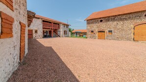 A courtyard with stone buildings, wooden balconies, and a gravel ground. - Les Coquelicots - A 30 min de Roanne (Régny)