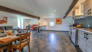 A spacious kitchen with a dining area, featuring a wooden table and chairs, a kitchen island, and modern appliances. - Les Coquelicots - A 30 min de Roanne (Régny)