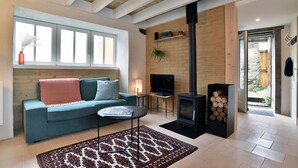 A cozy living room with a sofa, a TV, a fireplace, and a view of the outside.