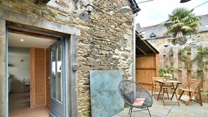 A stone exterior wall, a wooden deck, a metal gate, and a patio area with outdoor furniture.