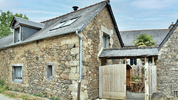 A stone house with a wooden door, a small porch, and a window.