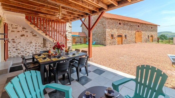 A covered outdoor dining area with a stone building in the background. - Le Clos de Verpierre - Appart avec Jardin (Régny)