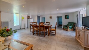 A spacious living area with a dining table, chairs, a green armchair, a television, and a cabinet. - Le Clos de Verpierre - Appart avec Jardin (Régny)