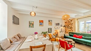 A dining area with a table set for four, a sofa, and a green couch. - Ti Riboul - proche plage (Douarnenez)