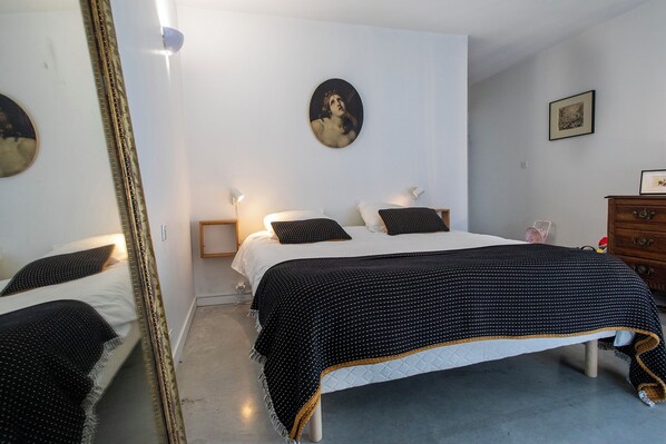 Un dormitorio con cama, cómoda, espejo y un cuadro en la pared.
