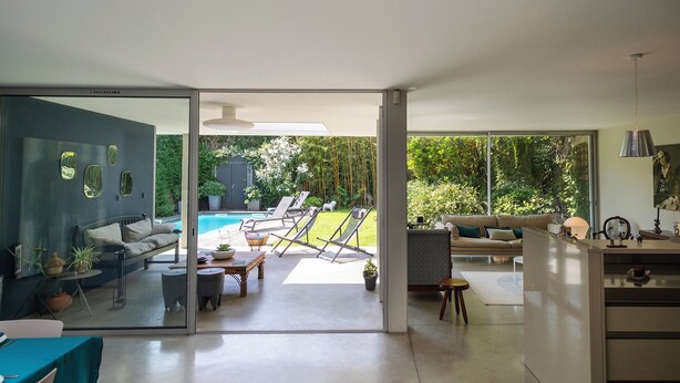 A modern living room with a glass door leading to a pool area.