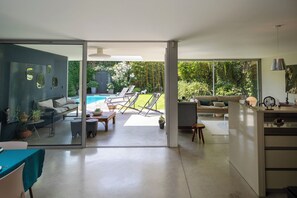 Una sala de estar moderna con un ventanal que da a una zona de piscina.