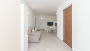 A modern living room with a sofa, a TV, and a wooden door.