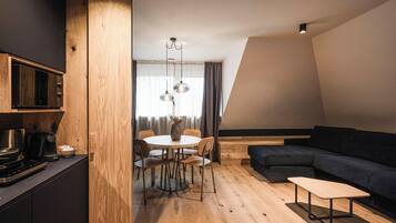Una cocina moderna con microondas incorporado, un comedor con mesa y sillas redondas, y un sofá de color oscuro en un espacio tipo loft.