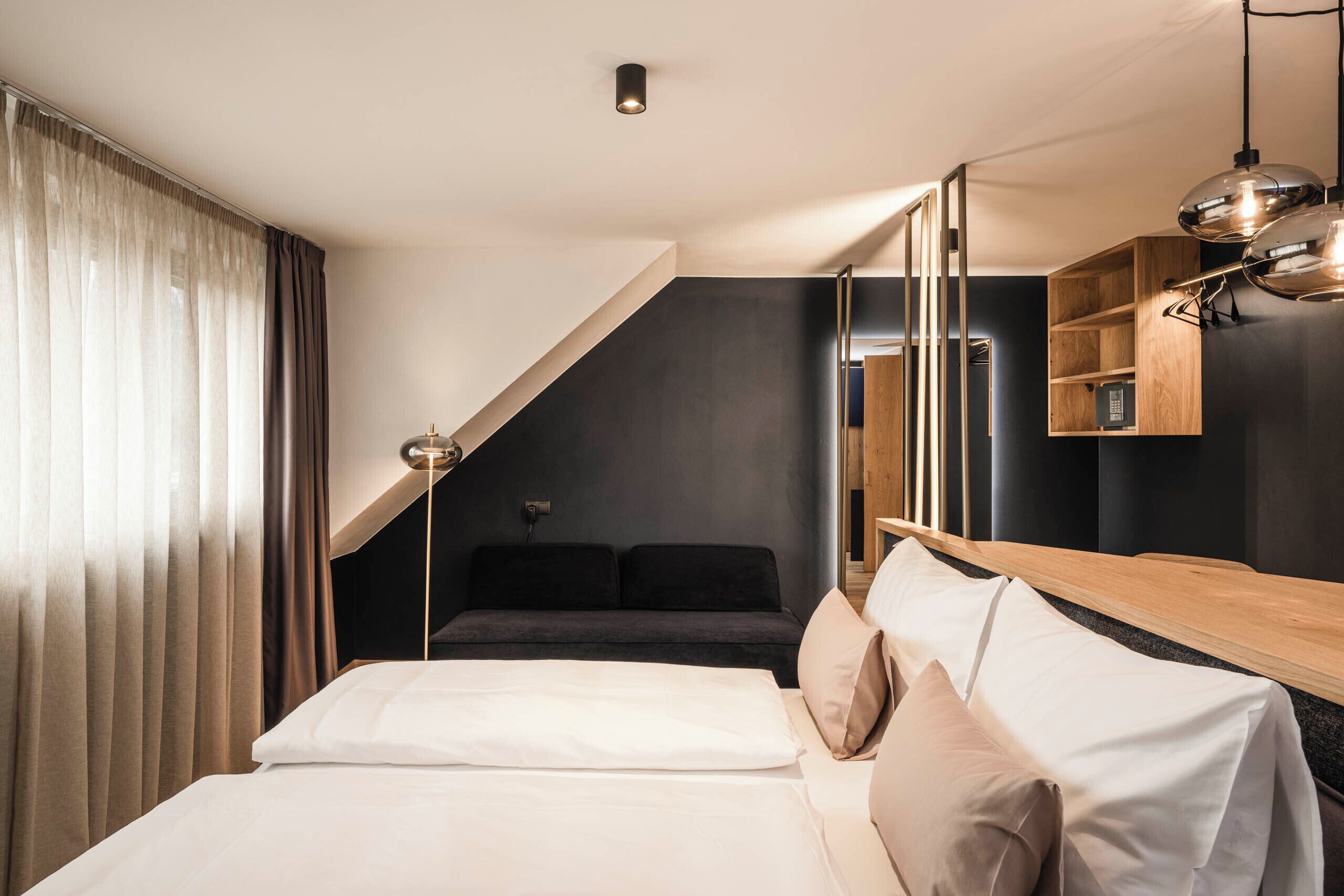 A modern hotel room with a bed, a desk, and a built-in wardrobe.