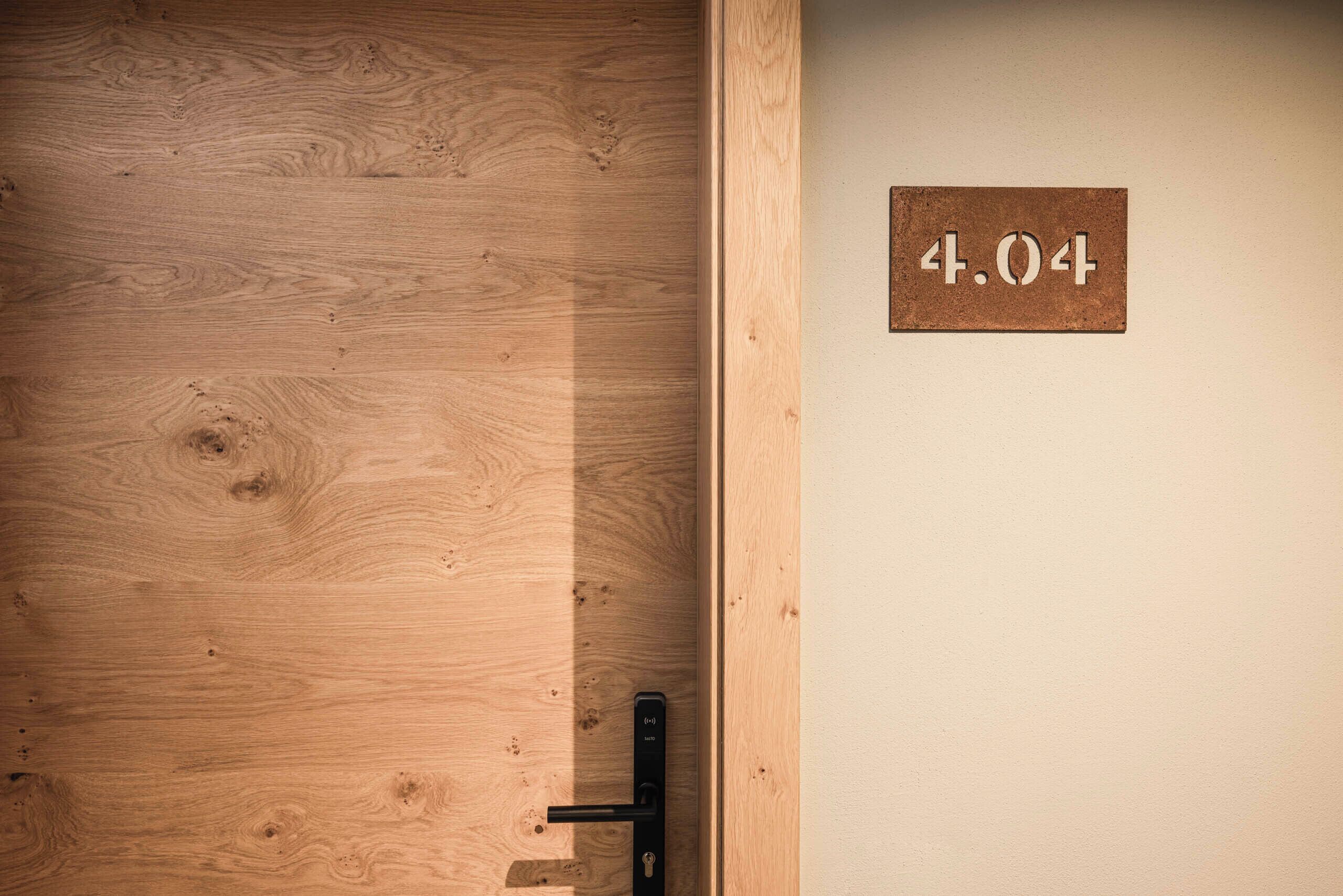Een houten deur met een metalen handvat en een bord erboven met de tekst '4.04'.