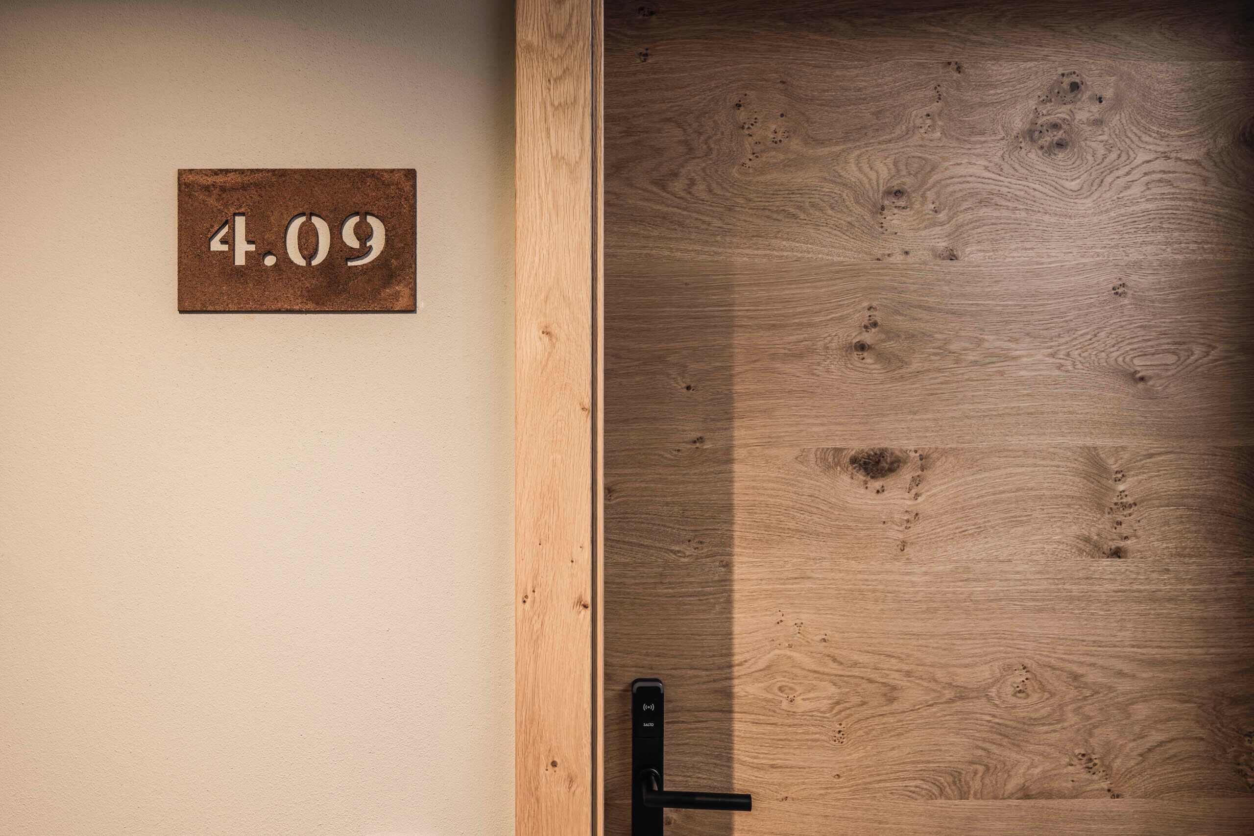 Une porte en bois avec une plaque portant le numéro « 4,09 » et une poignée de porte noire.