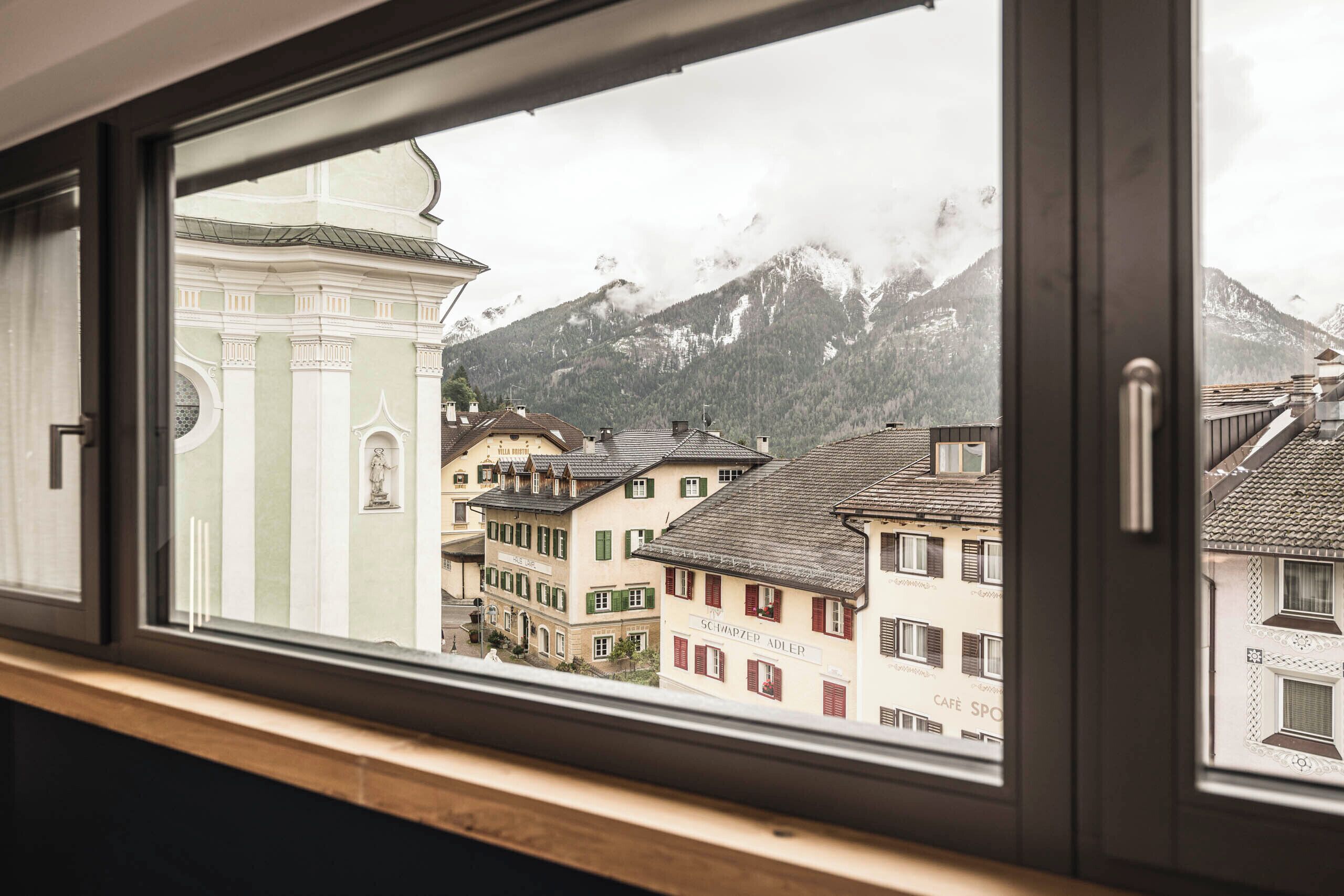 A window view of a town with traditional buildings and a mountain backdrop.