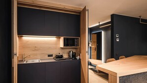 Una cocina moderna con armarios oscuros, encimera de madera y microondas integrado.